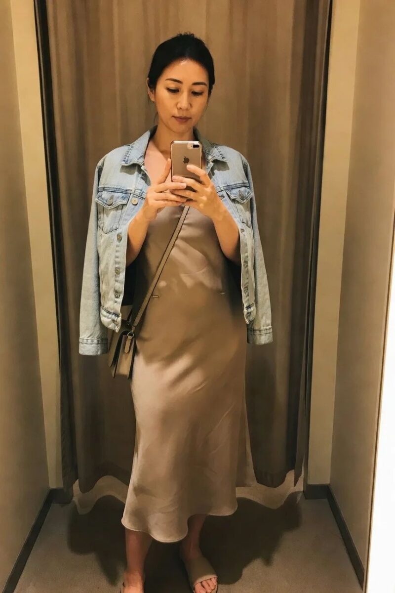 denim jacket draped over a beige slip dress