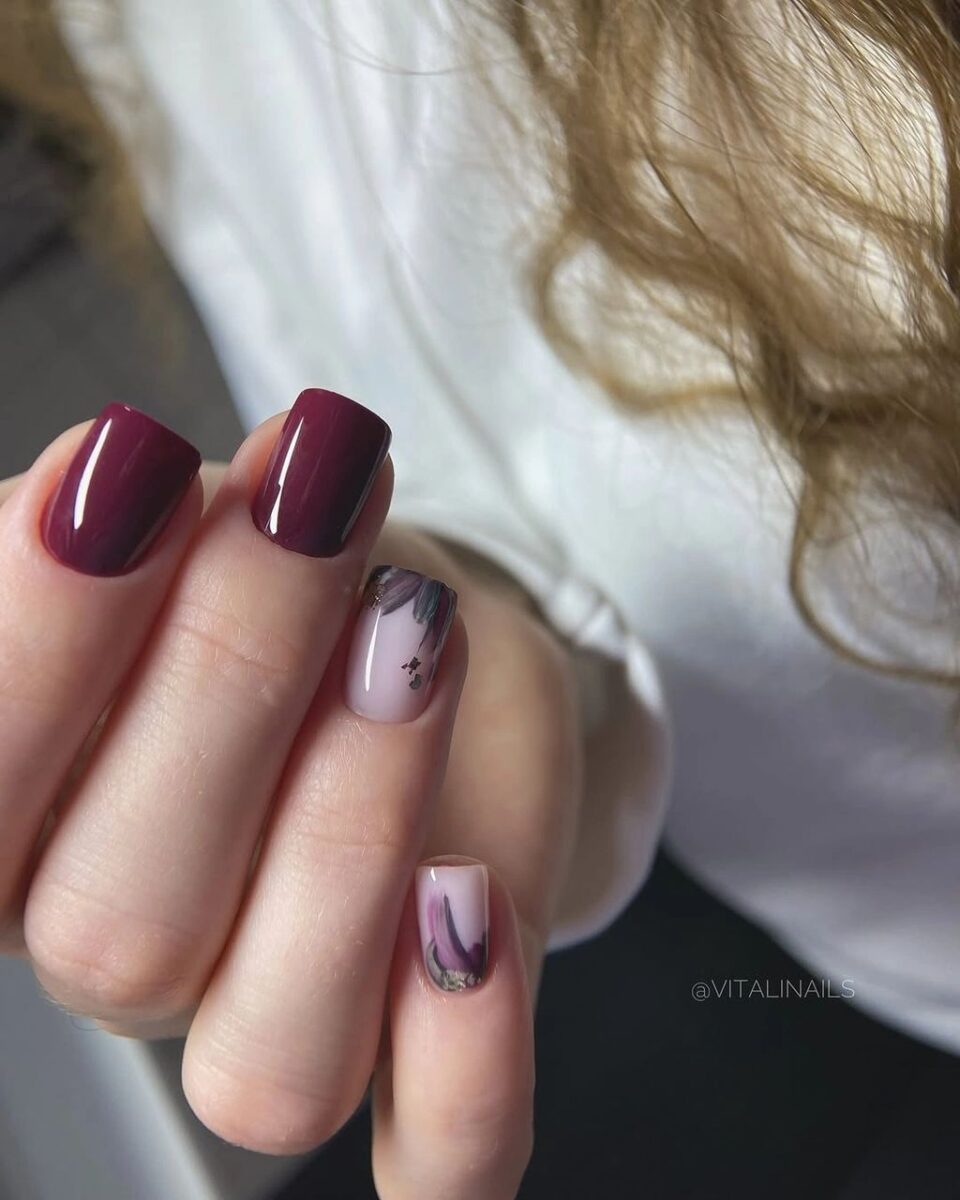 Medium burgundy French nails with pale bases and abstract accents