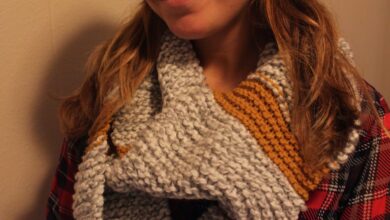 Woman wearing a chunky grey and mustard hand-knit infinity scarf with a black beanie