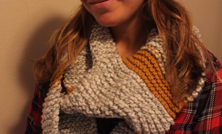 Woman wearing a chunky grey and mustard hand-knit infinity scarf with a black beanie