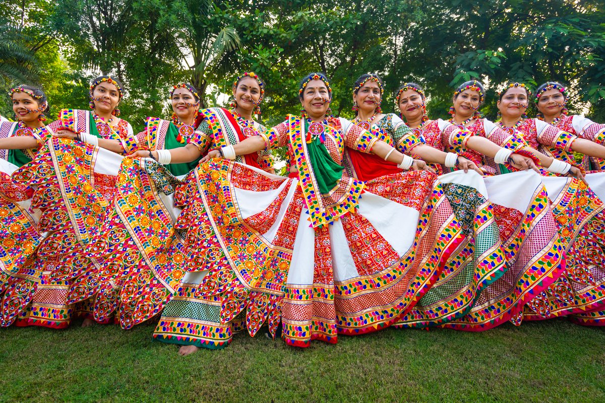 Women in colorful embroidered chaniya choli outfits with mirror work posing outdoors during Navratri