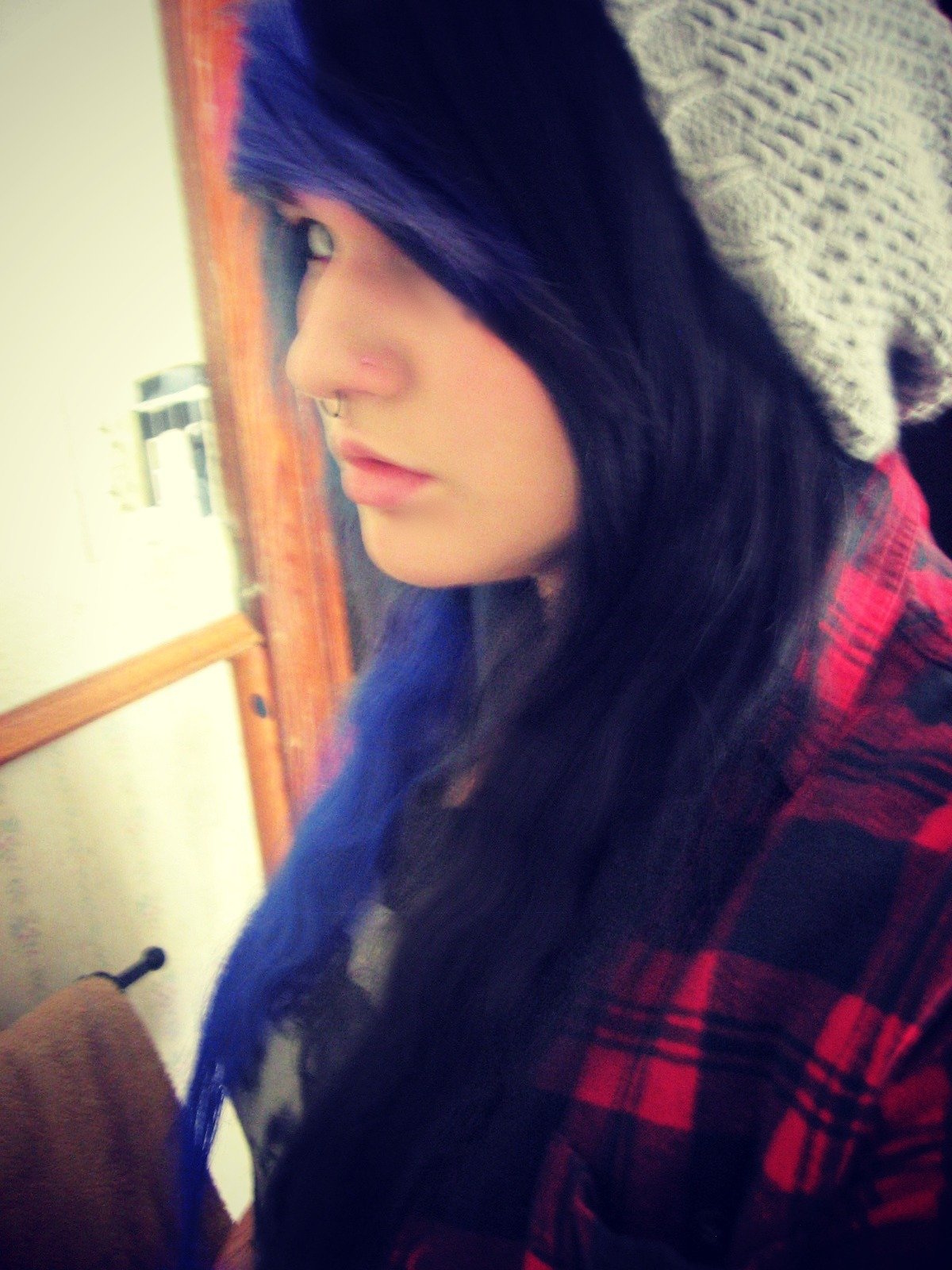 Young woman with blue-tinted hair wearing a grey knit beanie with a red plaid shirt