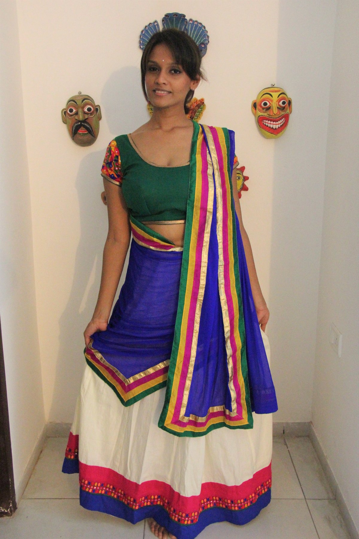 Woman in a white, blue and pink chaniya choli with a multicolored striped dupatta and green mirror-work blouse