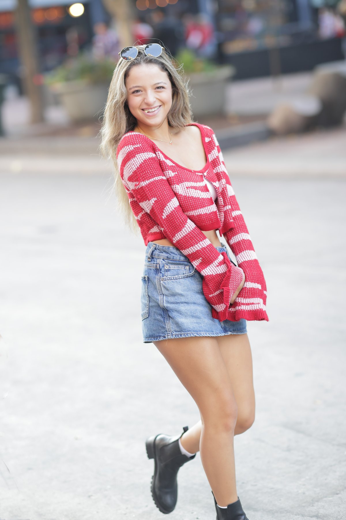 smiling young woman in a red-and-white striped knit top, denim mini skirt, white socks and black chelsea boots