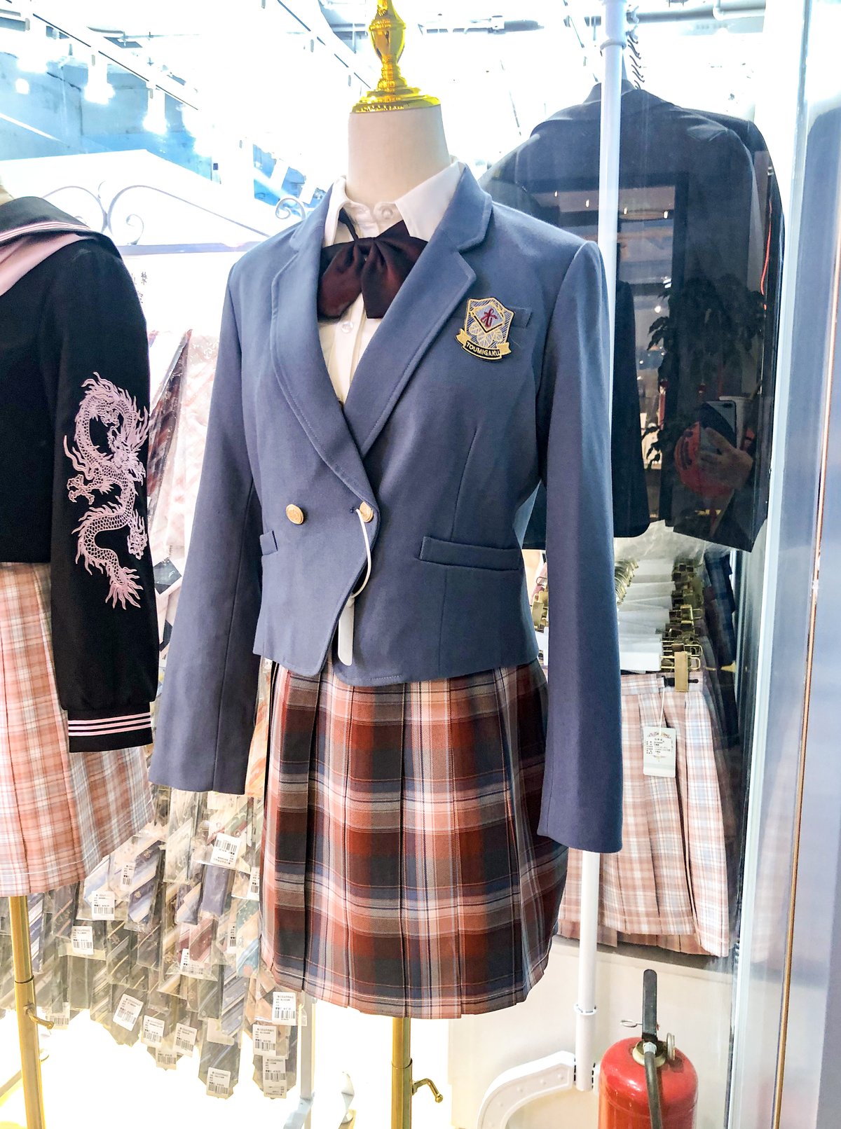 Mannequin in a Beijing shop window wearing a blue blazer over a rust, brown and beige plaid pleated mini skirt