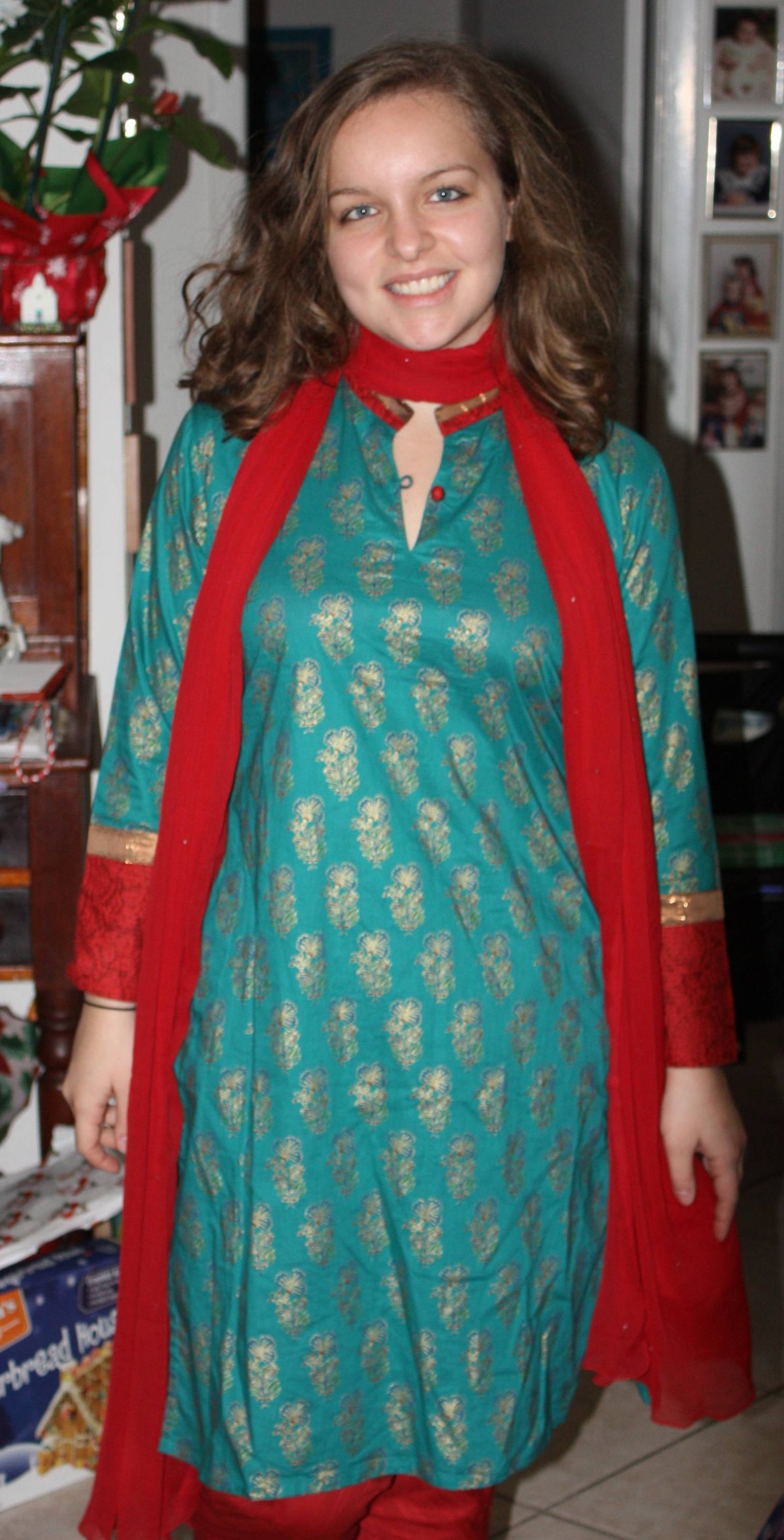 Woman in a teal printed kurta with gold motifs, red cuffs, red bottoms and a sheer red dupatta