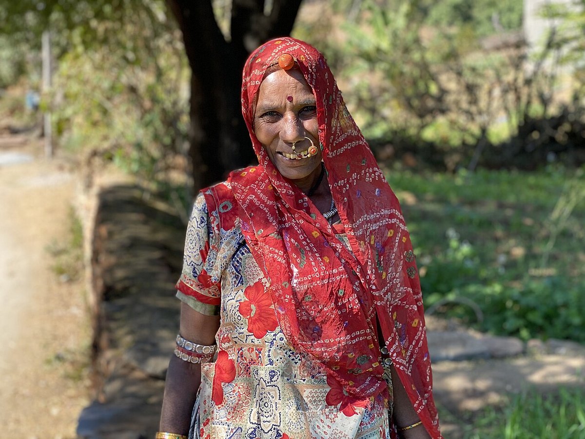 Woman outdoors wearing a red bandhani odhni over a printed blouse, with a nose ring, bangles and a red bindi