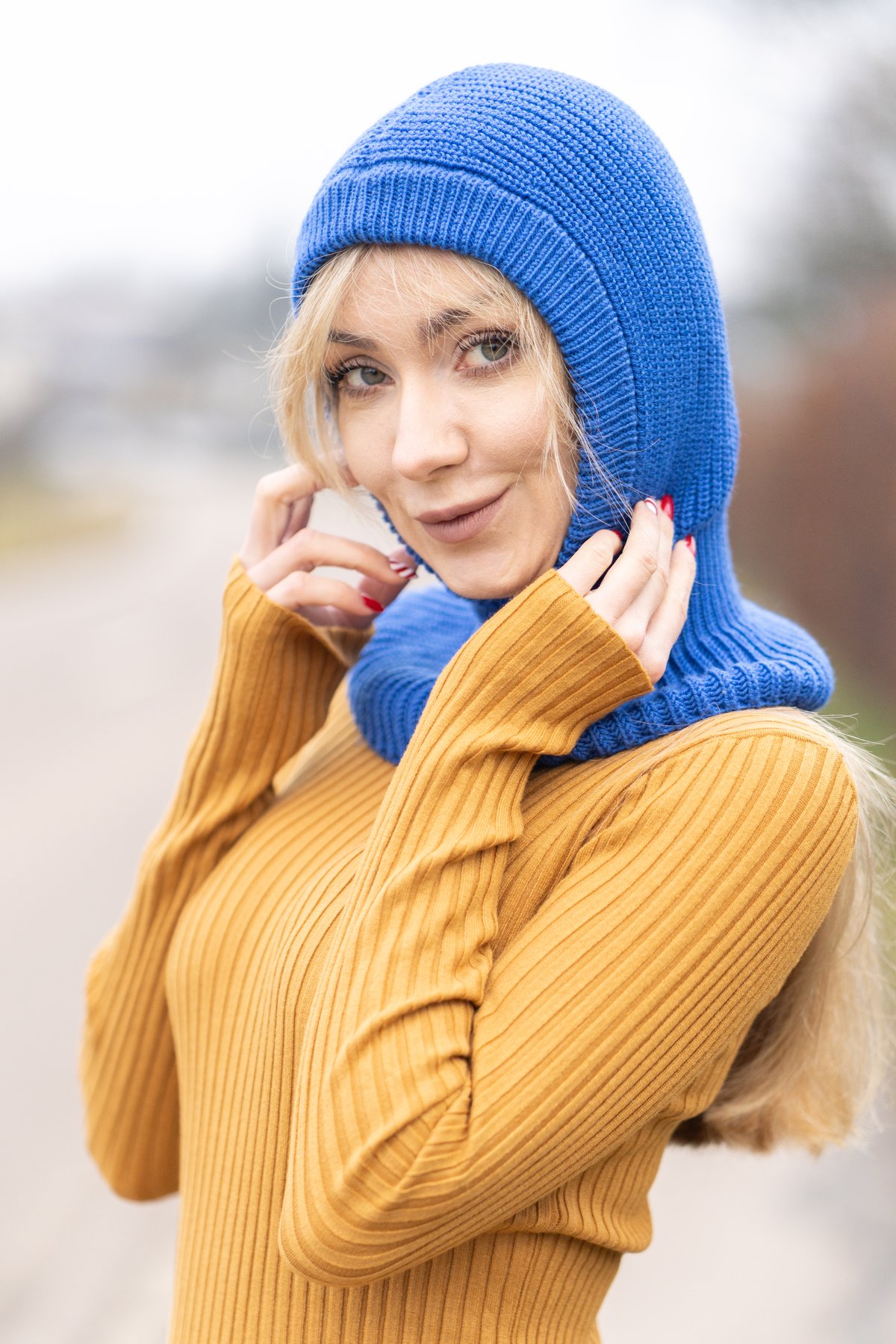 Blonde woman wearing a cobalt blue rib-knit balaclava with a mustard ribbed sweater