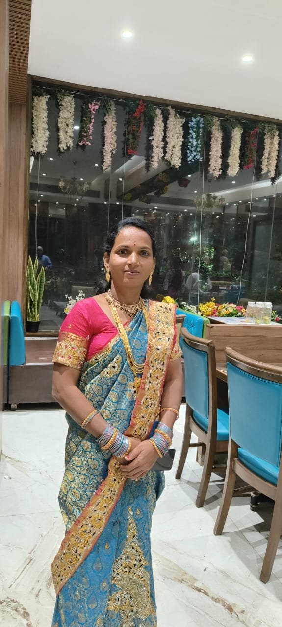 Woman in a blue and gold brocade saree with ornate zari border and pink blouse at an evening event