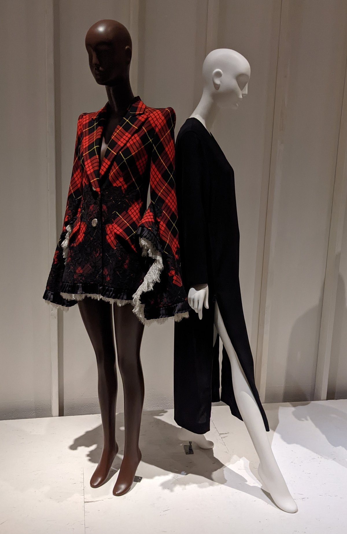 Museum mannequin wearing a red and black tartan blazer with black lace inserts and frayed trim at a 1990s fashion exhibition