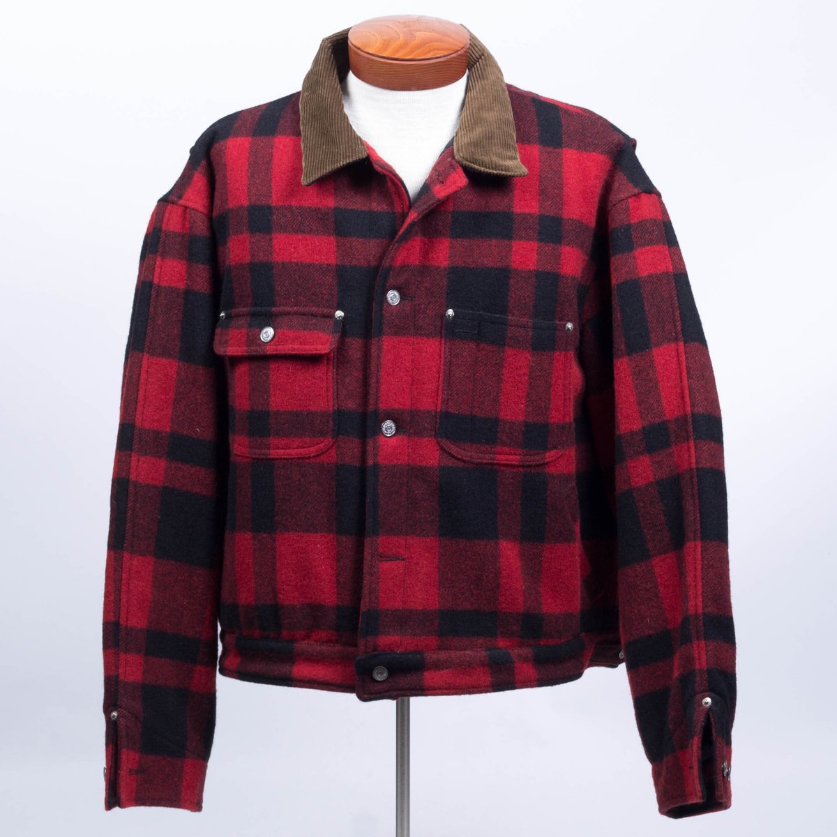 Red and black buffalo plaid wool winter jacket with a brown corduroy collar displayed on a tailor's dummy