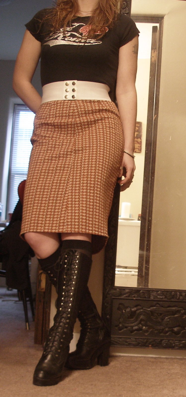Woman in a houndstooth pencil skirt and knee-high black lace-up leather boots.