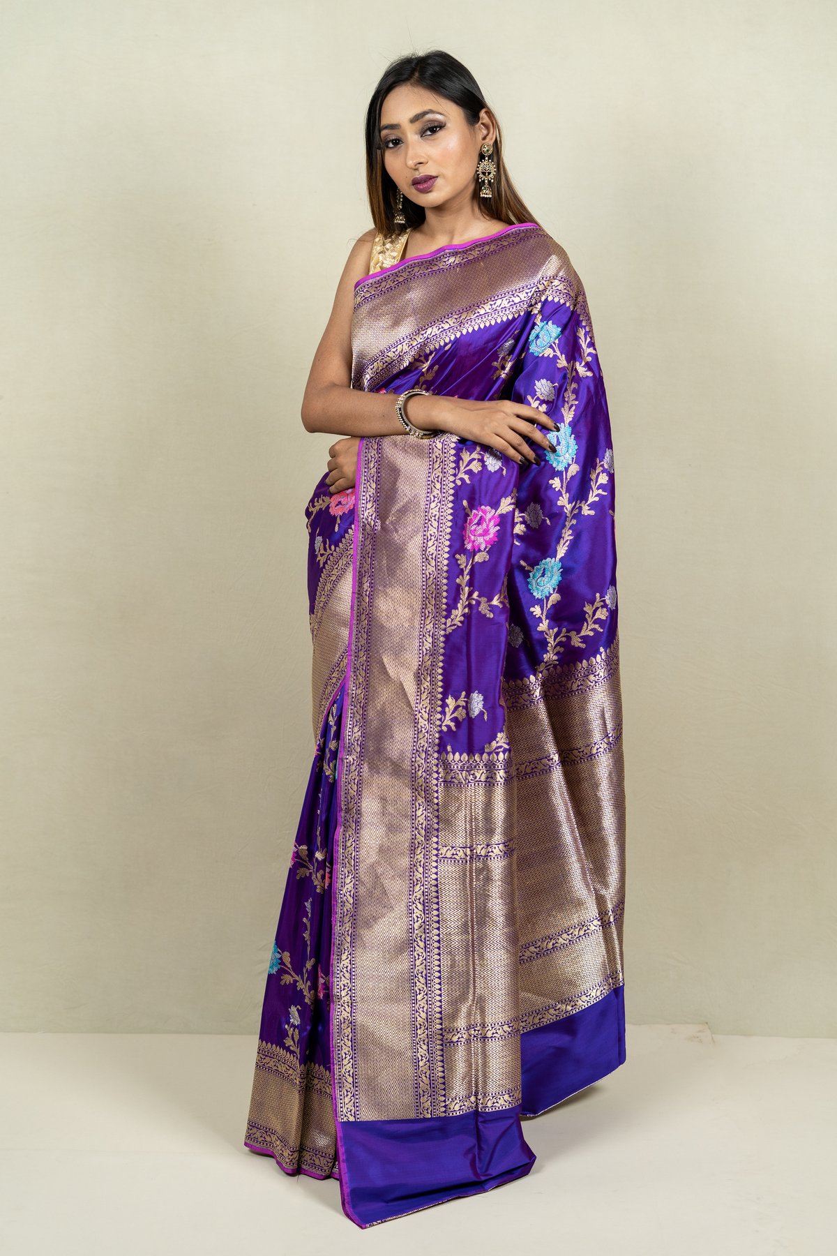 Woman in a royal blue-purple silk saree with gold zari floral work and wide gold border
