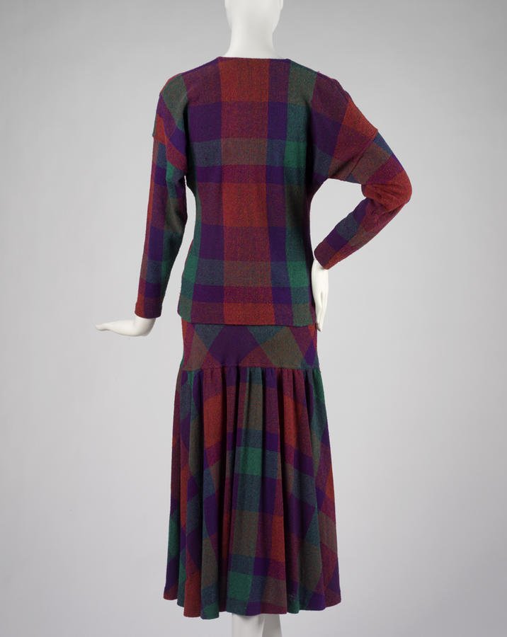 White mannequin wearing a 1970s Missoni purple, red and green plaid knit sweater and matching pleated skirt, viewed from behind