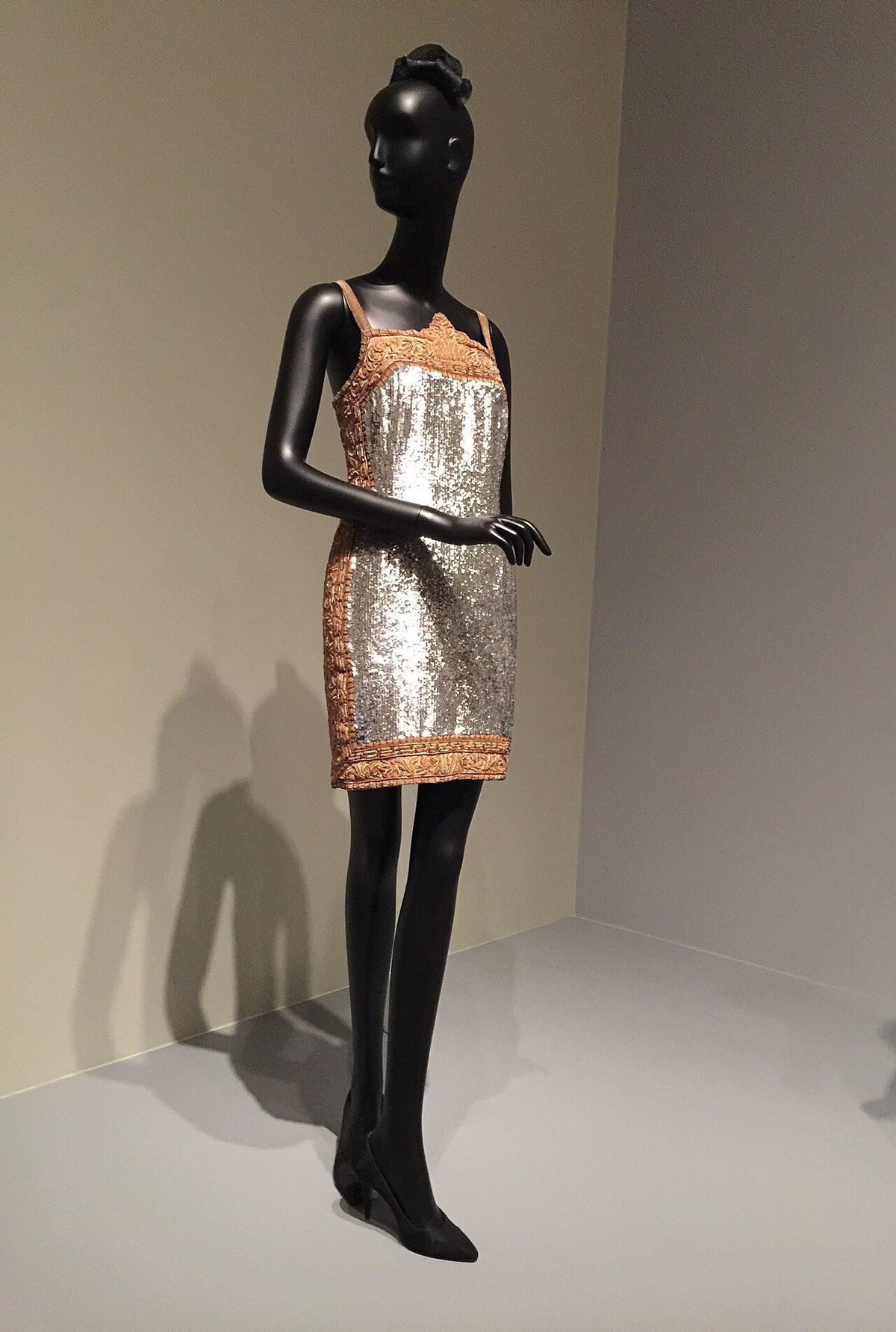 Silver sequinned mini dress with tan lace trim on a black mannequin against a plain wall