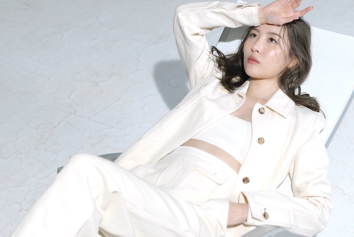Woman reclining in a cream co-ord set: buttoned cream jacket, cream crop top and cream trousers