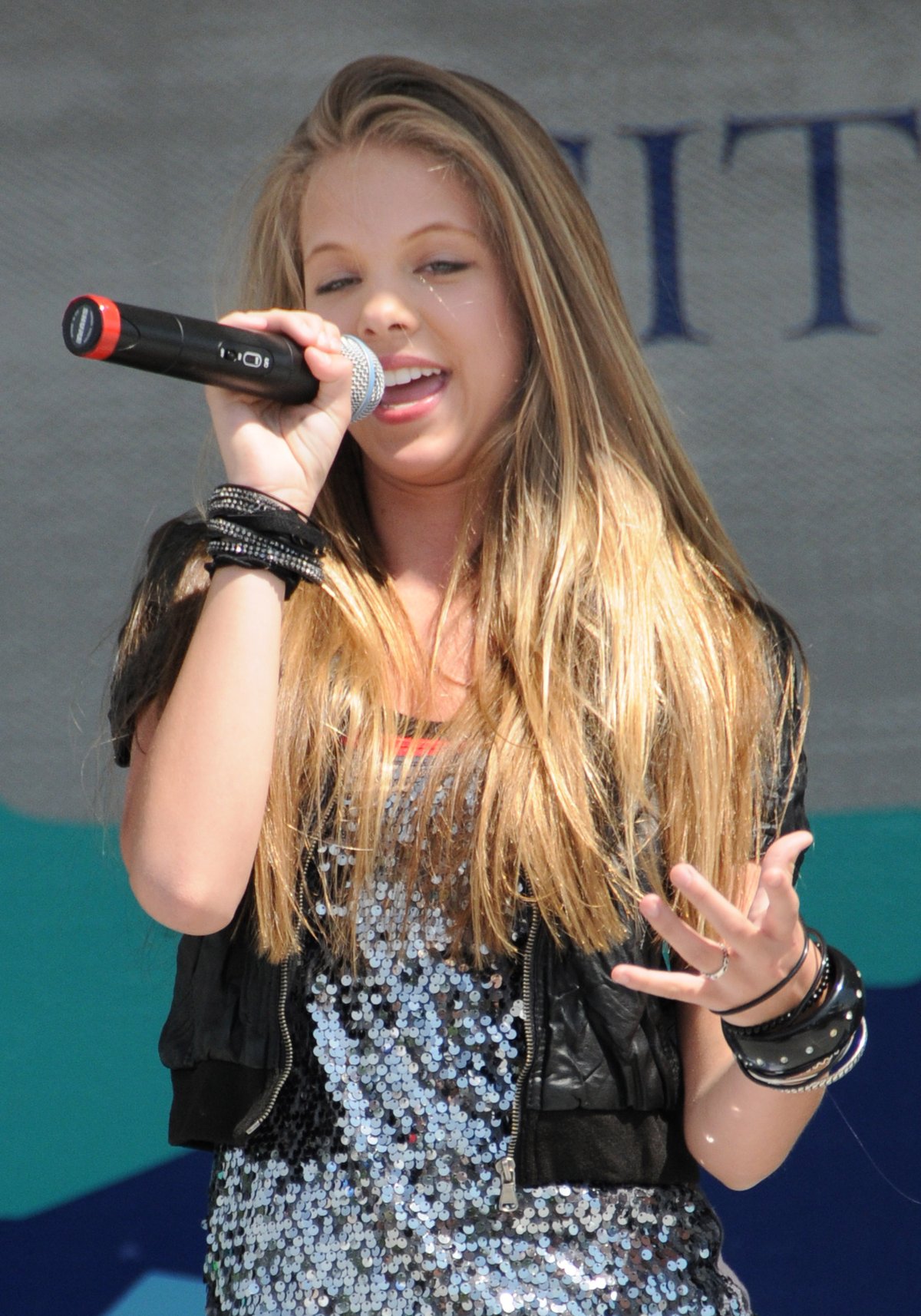 Singer Anna Magraret performing with a microphone in a silver sequin sleeveless top