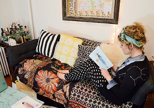 Woman relaxing on a couch at home wearing a black constellation-print sweater and a headscarf