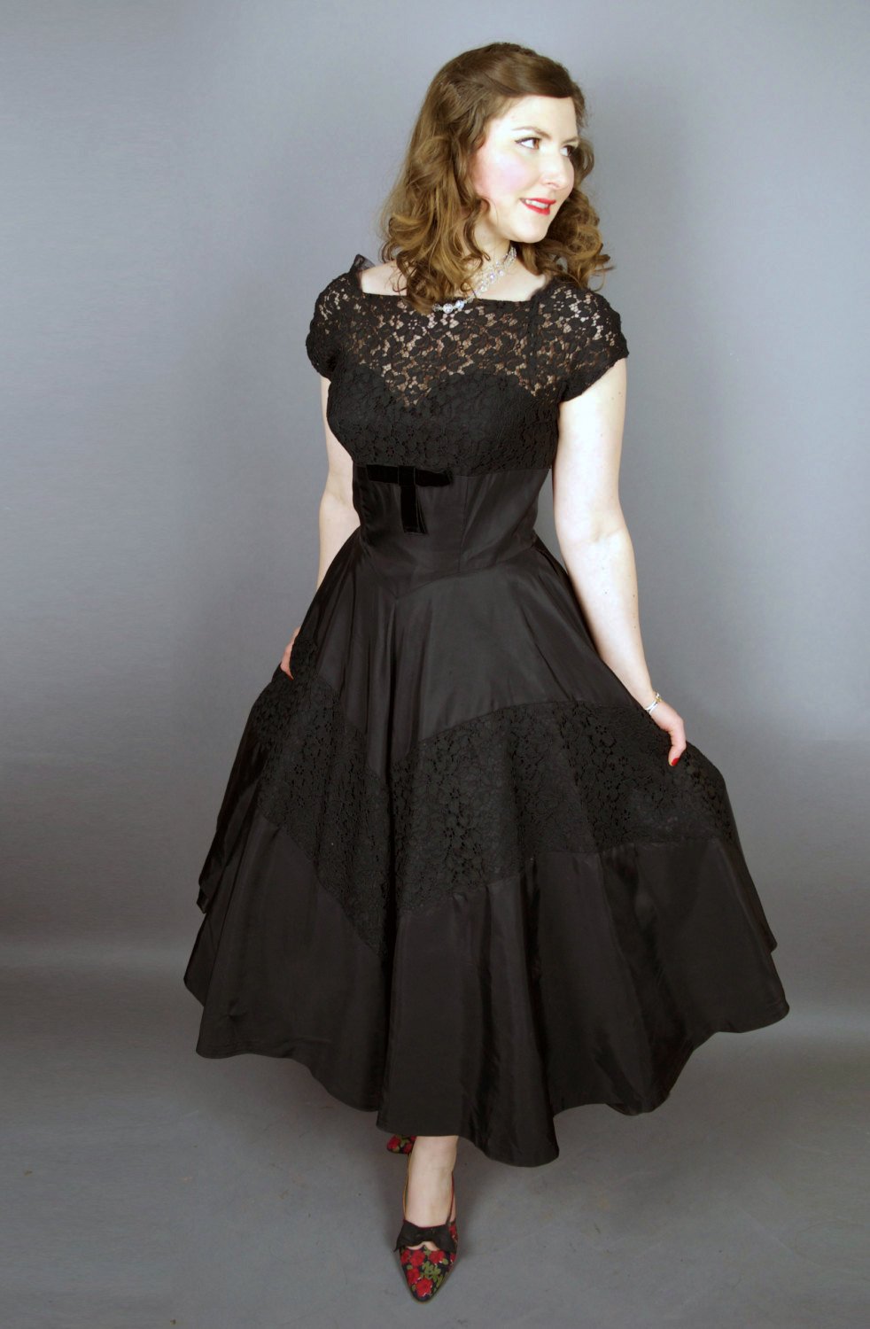 Woman in a vintage black lace and satin evening dress with a bow belt.