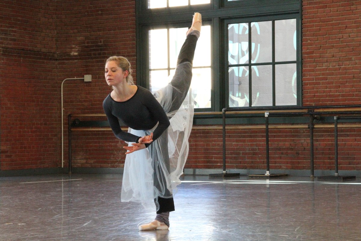 Dancer wearing a black leotard with a sheer white tulle wrap skirt