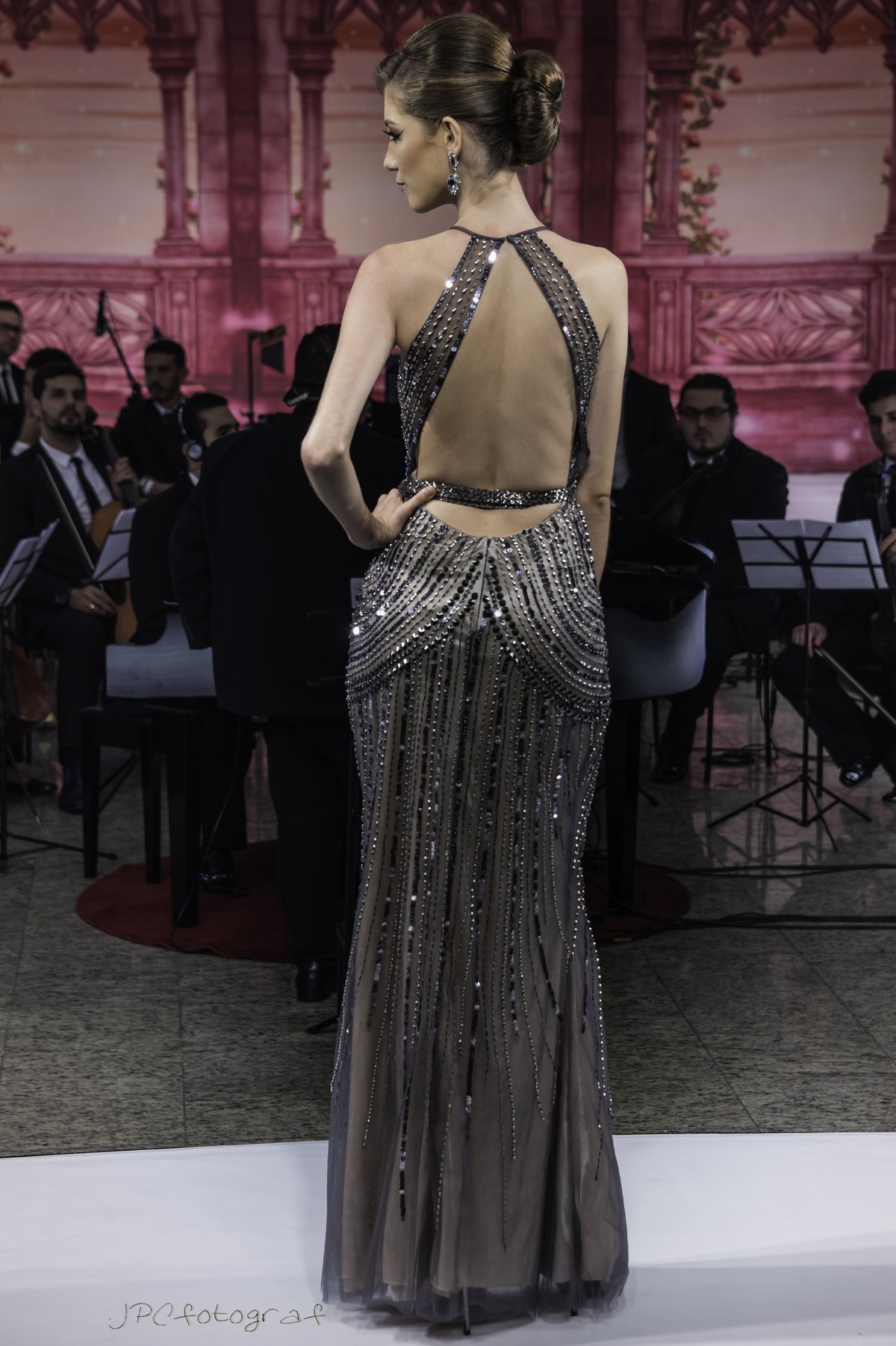 Model wearing a black fitted sequined gown with an open back