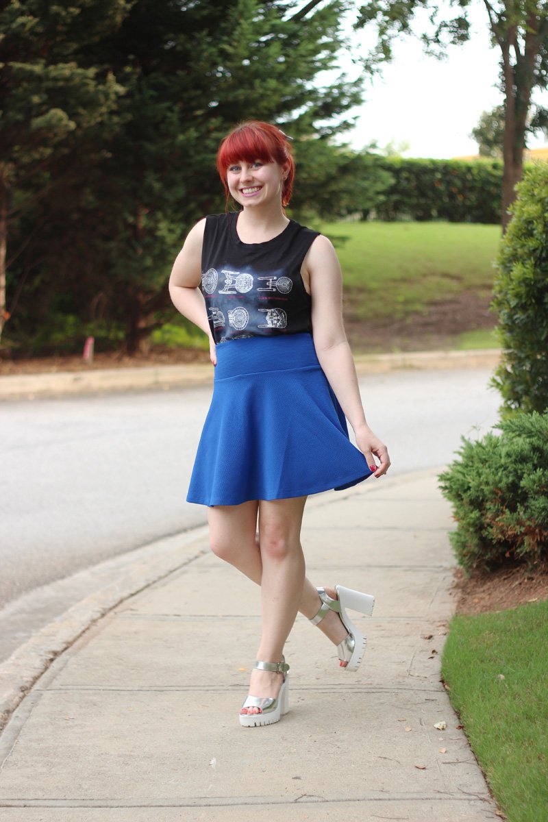 Woman in a royal-blue skater skirt and silver chunky heels with a printed sleeveless top