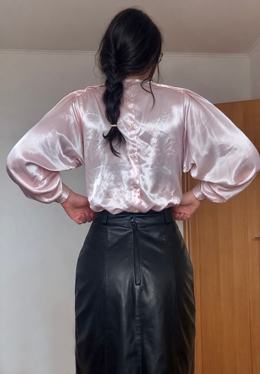 Woman wearing a blush satin blouse with a black leather pencil skirt