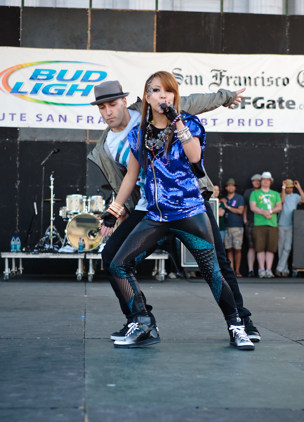 Singer BoA performing on an outdoor stage in a blue sequin jacket with dark skinny jeans