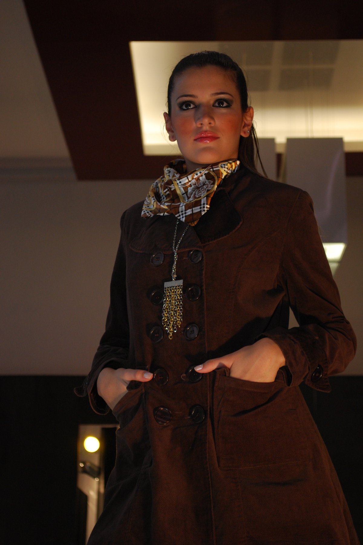 Woman in a brown coat with a patterned scarf and turtleneck