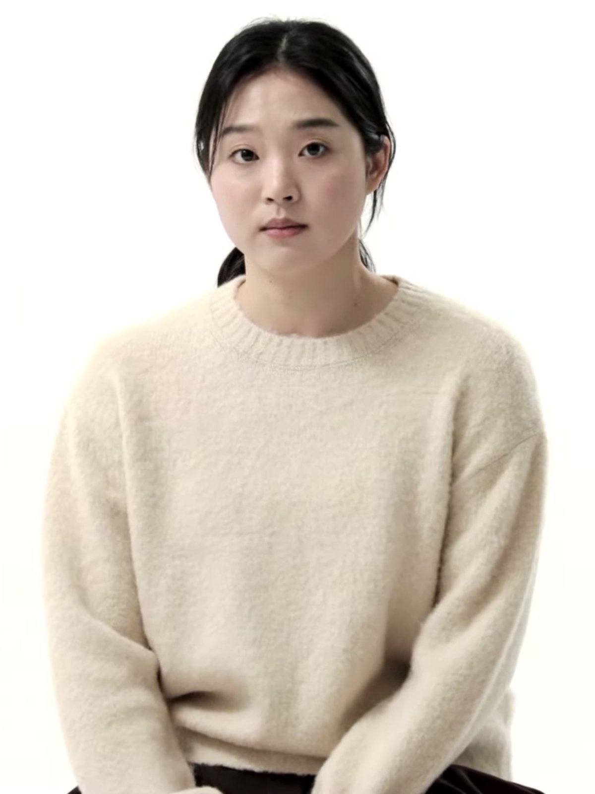 Woman wearing a soft cream fuzzy knit sweater against a white background