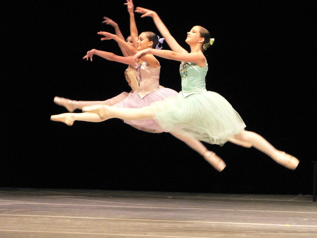 Dancers in pastel tutus performing a grand jete leap