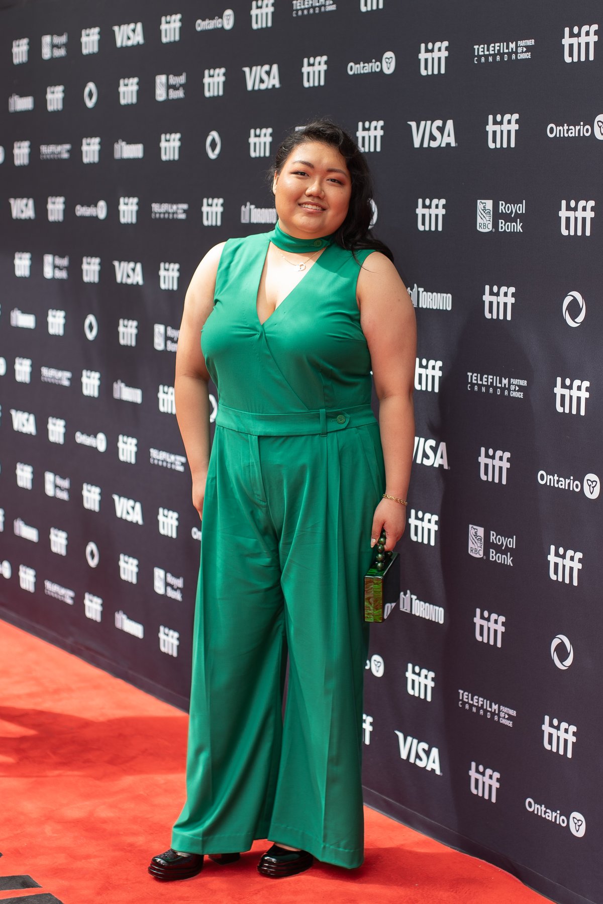 A woman wearing an emerald green sleeveless wide-leg jumpsuit on a red carpet