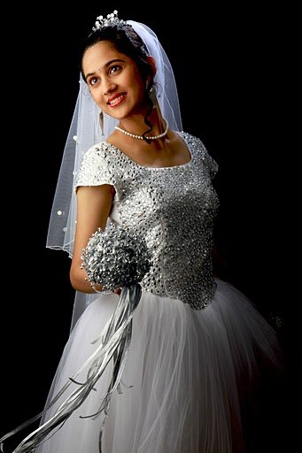 A woman in a silver sequin fitted bodice gown with a sheer white veil and bouquet