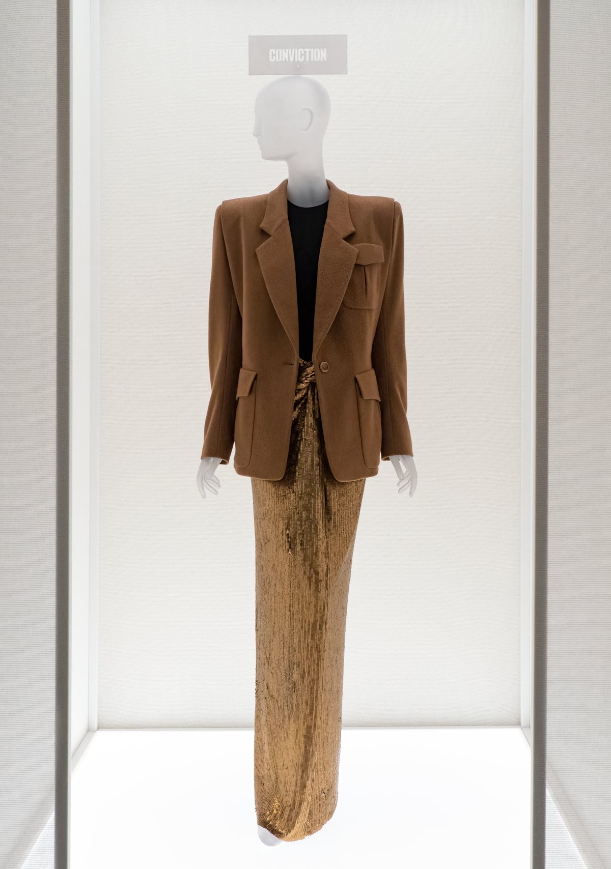 Mannequin wearing a gold sequin long skirt with a camel blazer and black top, Met museum exhibition display
