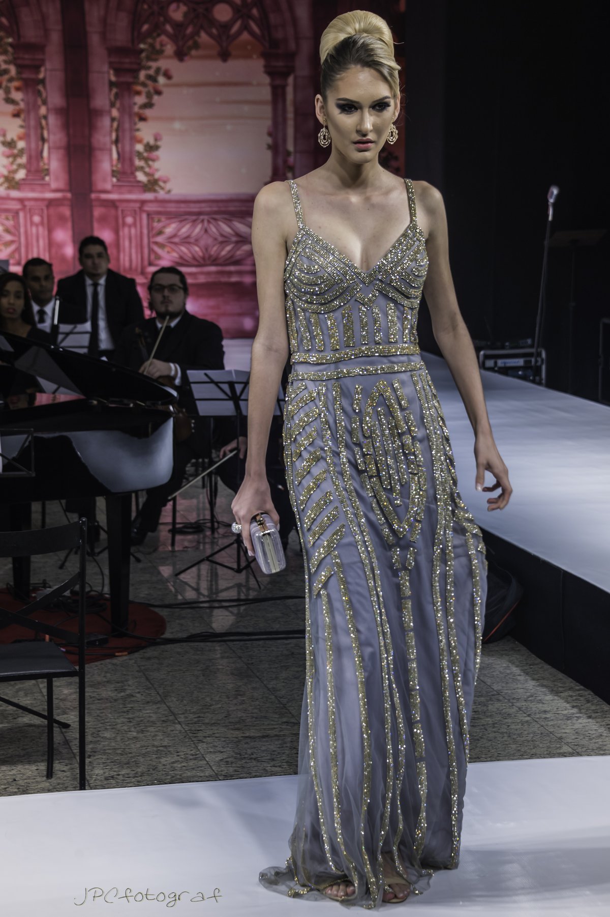 Model wearing a grey and gold striped sequined floor-length gown with spaghetti straps