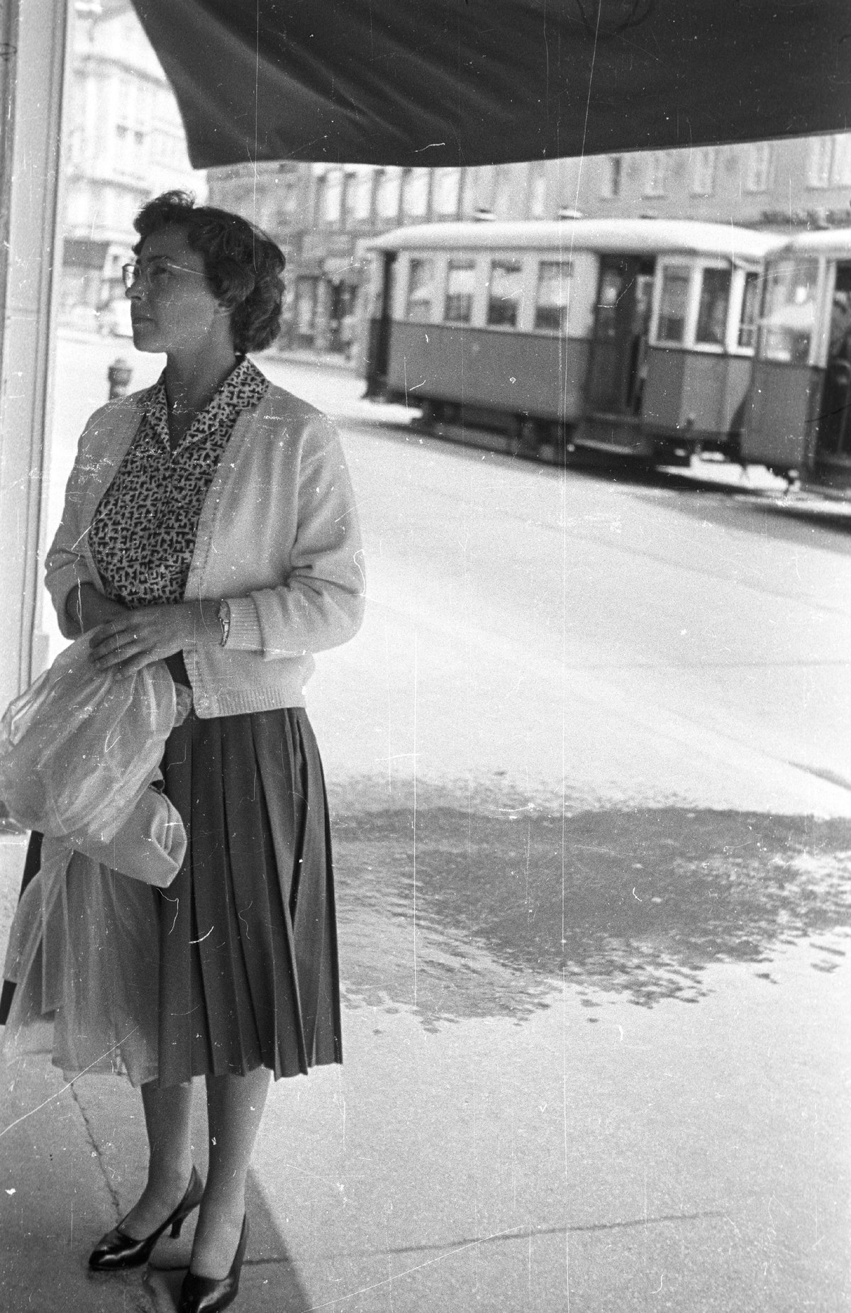 Light cardigan worn open over a printed blouse with a pleated skirt