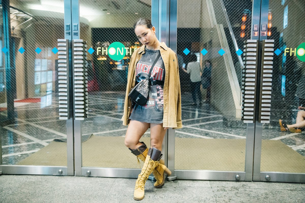 Woman in a mustard-yellow cardigan, denim skirt and tan knee-high boots in Tokyo