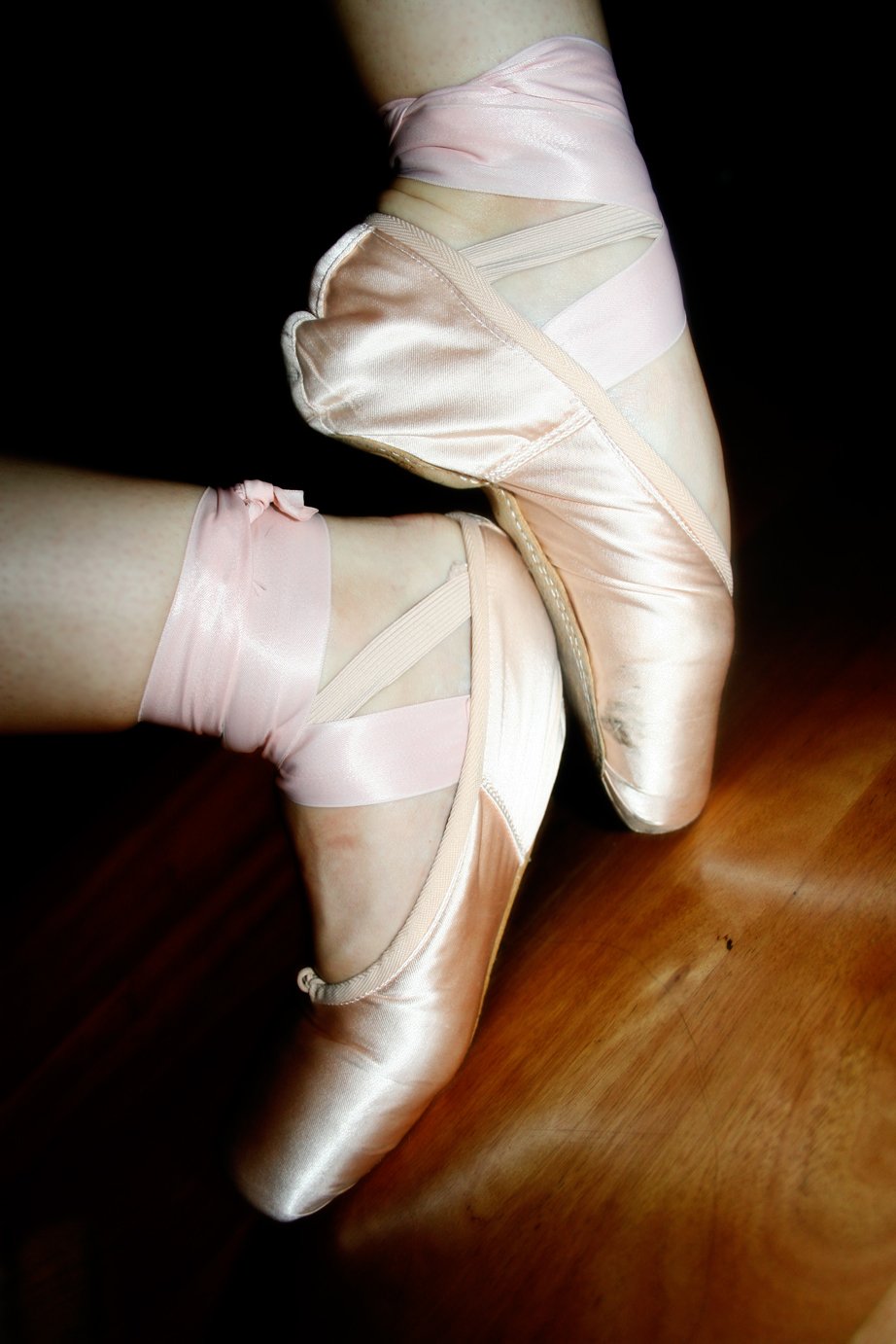 Pink satin pointe shoes with ribbons tied around the ankles
