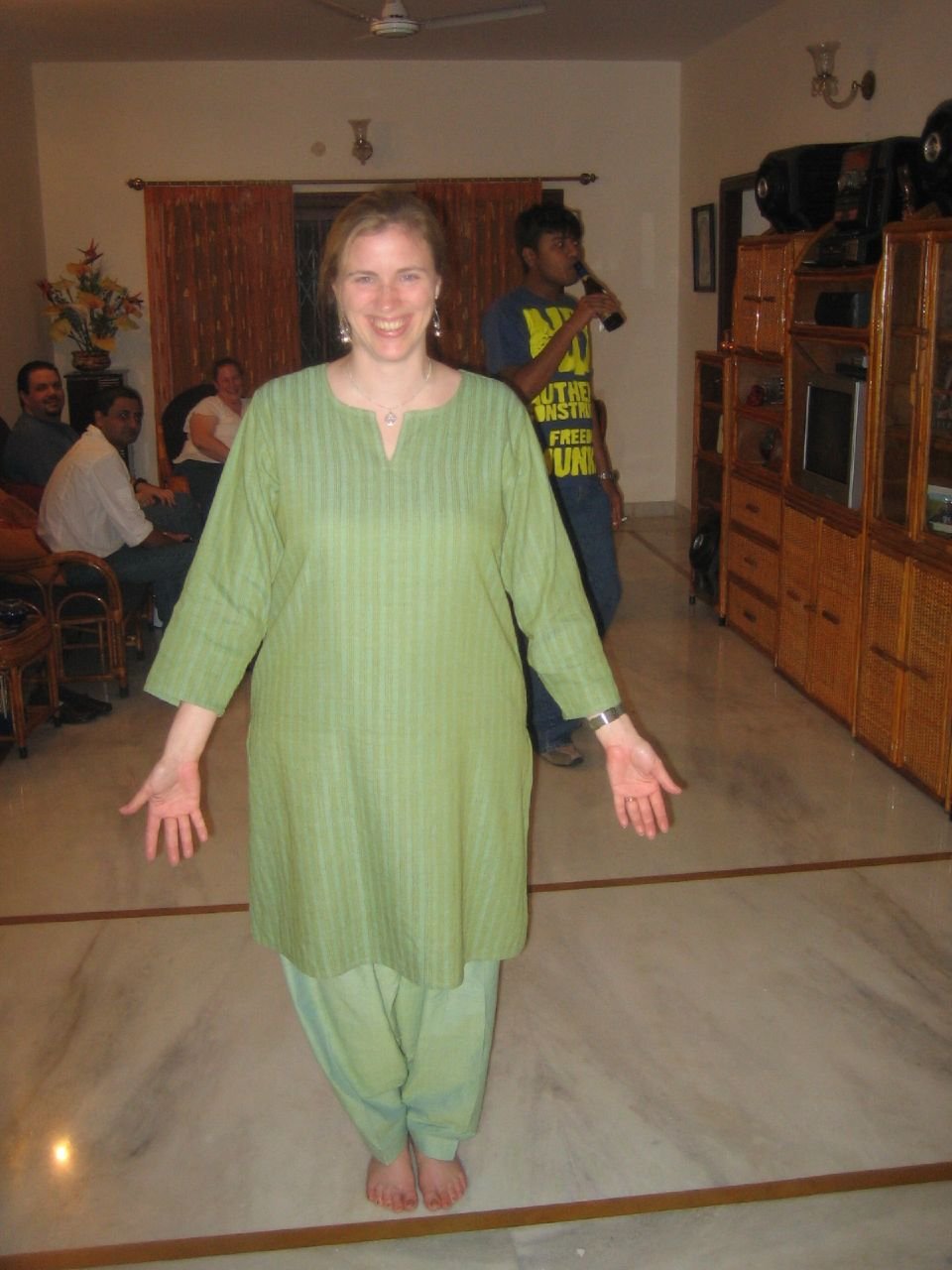 Smiling woman standing barefoot in a light green striped cotton kurta and salwar in a living room