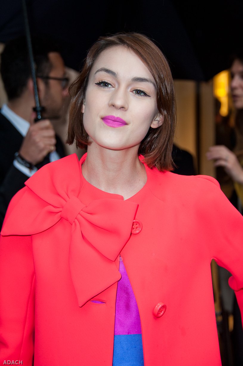 Woman wearing a bright red coat with a large bow at the neckline