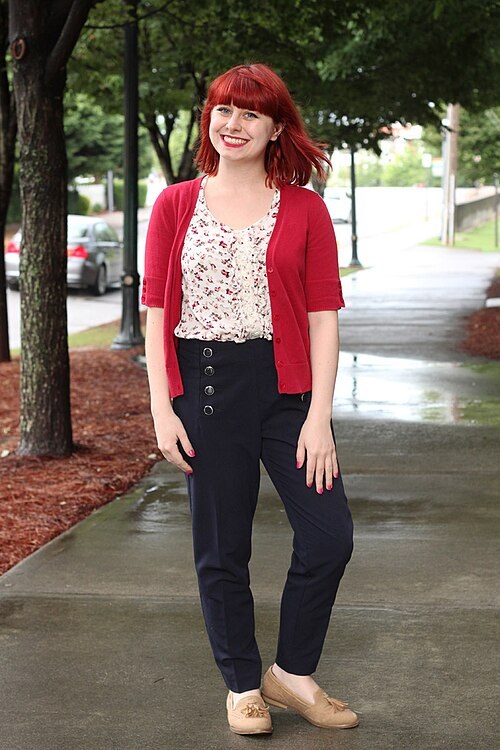 Woman in a red cardigan over a floral blouse with navy sailor pants and tan loafers