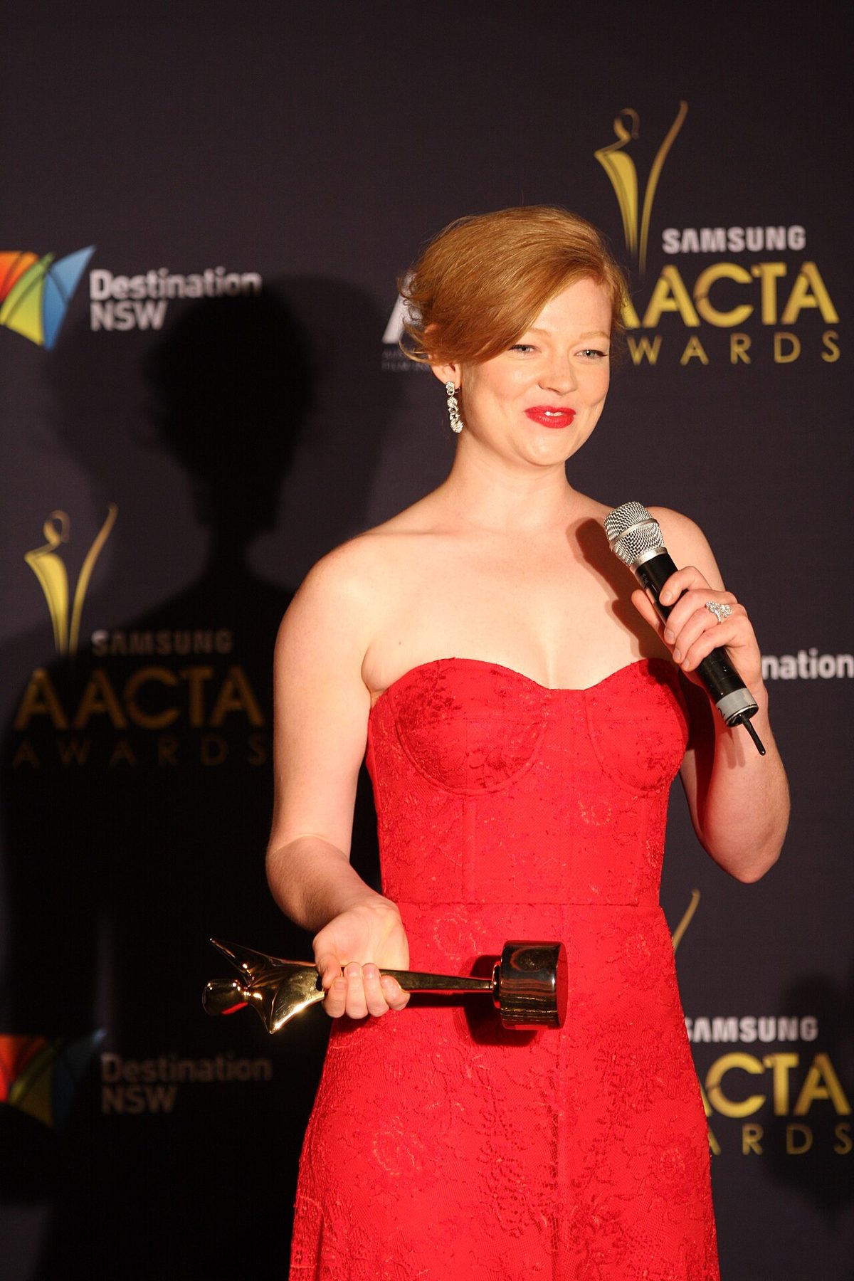 Sarah Snook wearing a red strapless lace gown with a sweetheart neckline at an awards show