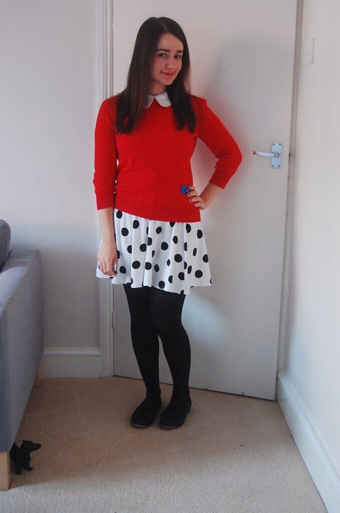 Woman wearing a red sweater with a white collar, a white polka-dot skirt and black tights