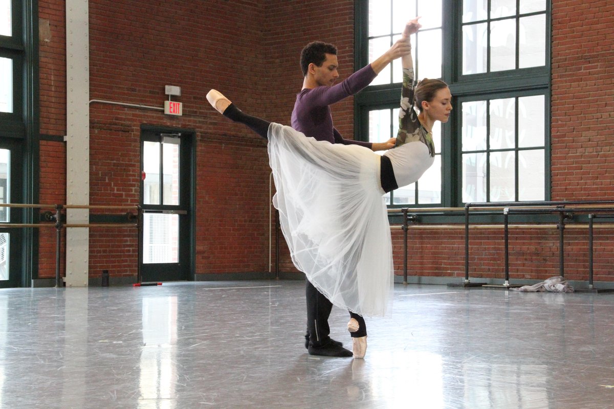 Dancers in romantic long white tutus during a partner lift rehearsal