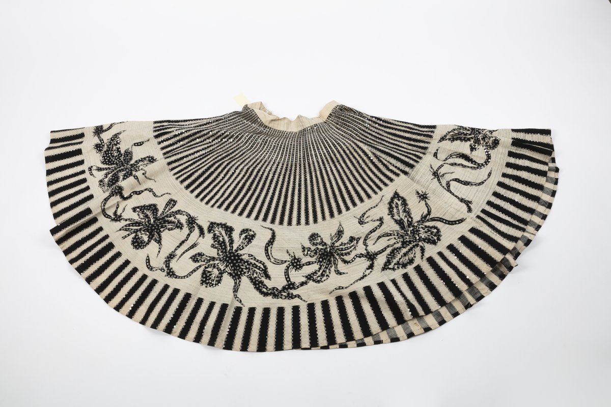 Flat-laid tan skirt with black trim and silver sequin floral motifs