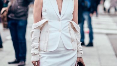 Woman in a white ribbed midi dress and brown knee-high boots walking on a city street